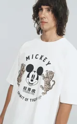 Remera de manga corta con cuello redondo y calce oversize, confeccionada en algodón premium. Presenta un estampado frontal con la cara de Mickey Mouse rodeada de dos tigres y texto alusivo.