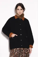 Campera negra con cuello y puños de pana marrón, cierre frontal con botones a presión y bolsillos delanteros con solapa. Diseño acolchado con costuras en forma de rombos.