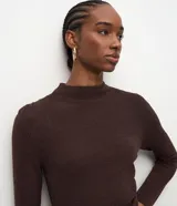 Vestido midi de punto color marrón chocolate, con manga larga, cuello alto sutil y detalle de fruncido lateral que ajusta la silueta. Diseño minimalista de corte recto.