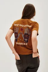 Remera de algodón color marrón con estampa gráfica en la espalda que incluye manos, un ojo y la frase 'Trust your intuition, your fate is in your hands'.