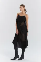 Vestido midi negro de gasa y satén, con escote recto, volados y ruedo irregular.