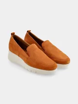 Mocasines slip-on de cuero nobuck color suela con diseño perforado en el empeine, elásticos laterales para facilitar el calce y suela plataforma de poliuretano blanca.