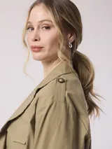 Campera color beige, estilo cazadora, con cuello camisero, cierre frontal con botones, cuatro bolsillos frontales con solapa y mangas 3/4 con trabillas.