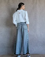 Pantalón de jean azul de tiro medio, con corte wide leg y ruedo deshilachado.