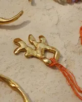 Collar con dije de bronce macizo con forma orgánica irregular, similar a un coral, suspendido de un cordón negro de seda natural anudado.