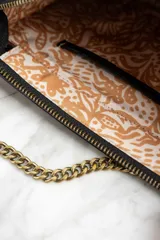 Cartera tipo sobre con estampado animal print, correa de cuero sintético negra y cadena dorada.