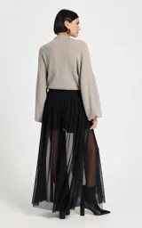 Pantalón de tiro alto confeccionado en tul negro, con silueta ajustada en la cadera y caída fluida. Presenta una cinturilla con detalle de aberturas horizontales y diseño de largo hasta el tobillo.