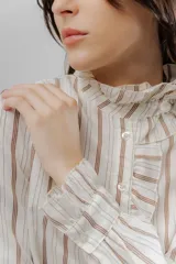 Camisa de corte clásico con estampado de rayas verticales, cuello alto con volados frontales y mangas largas con puños con volados.