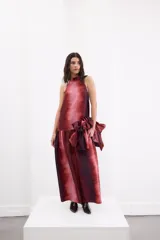 Vestido largo de corte holgado con estampado degradé en tonos rojizos y bordó. Presenta escote halter con cuello alto, espalda descubierta con cierre de botones y un maxi volado en la cadera que aporta volumen a la falda.