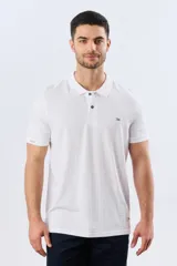 Remera polo de piqué manga corta, color blanco con estampado geométrico sutil. Presenta cuello camisero y cartera con dos botones oscuros.