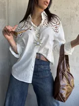 Camisa blanca de lino con detalles de encaje en los hombros y mangas 3/4.