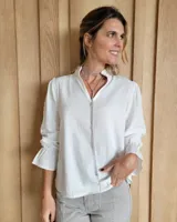 Blusa de algodón color azul, de corte suelto, con mangas largas abullonadas y cuello con volados y escote en V.