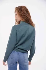 Sweater de punto color verde azulado, con cuello alto y mangas largas.