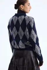 Cárdigan de punto con diseño de rombos (argyle) en tonos azul marino y gris. Presenta cuello camisero y cierre frontal de botones.