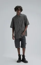 Camisa de manga corta con calce oversize, confeccionada en algodón con bordado tipo broderie y acabado con efecto desgastado. Presenta cuello clásico y cierre frontal con botones.