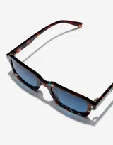 Lentes de sol unisex Hawkers X Pierre Gasly, con montura rectangular de carey con detalles en azul y lentes degradadas en azul.