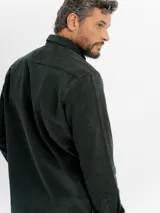 Camisa de manga larga confeccionada en pana de algodón, con cuello clásico, cierre frontal de botones y bolsillo en el pecho.