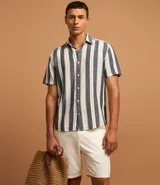 Bermuda masculina de sarga en color blanco, con cierre frontal de botón y cremallera, trabillas para cinturón y bolsillos laterales.