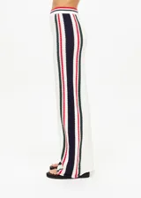 Pantalón de punto abierto de algodón orgánico color crema con rayas verticales en rojo, azul marino y verde pino. Cintura elástica acanalada con rayas de punto y silueta de pierna ancha.