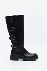 Bota de caña alta estilo biker, confeccionada en cuero sintético negro. Presenta múltiples tiras decorativas con hebillas metálicas laterales y una suela robusta con relieve tipo track.