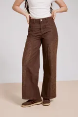 Pantalon de jean azul de corte ancho, con paneles laterales estampados con diseño floral sutil y costuras visibles.