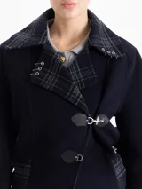 Chaqueta de lana azul marino con solapas en contraste a cuadros, cierre frontal con botones y detalles de ganchos metálicos decorativos. Incluye cinturón de tela con hebilla metálica para ajustar la cintura.