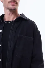 Camisa de jean de manga larga en tono azul claro, con cuello clásico, cierre frontal con botones y dos bolsillos delanteros con solapa.