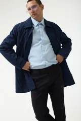 Gabardina azul marino con cuello clásico, cierre frontal con botones y bolsillos laterales.