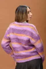 Sweater de punto con textura suave y diseño de franjas horizontales en tonos violeta, lila y naranja. Presenta cuello redondo y mangas largas con un corte relajado.