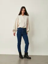 Jean chupín negro de tiro alto, confeccionado en denim con cinco bolsillos tradicionales y cierre frontal con botón y cremallera.