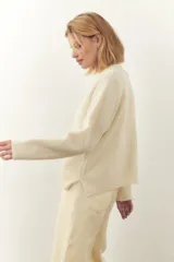 Cárdigan color crema de tejido de punto industrial con escote en V, combinación de puntos y botones decorativos en las mangas.