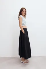 Falda midi de tiro alto en color verde militar, con diseño acampanado y cintura elástica. Presenta costuras verticales que definen su estructura y cierre lateral con cremallera oculta.
