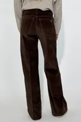 Pantalón de corte recto y tiro medio, confeccionado en pana color bordó. Presenta costuras verticales decorativas en el frente, cierre con botón y bolsillos laterales.