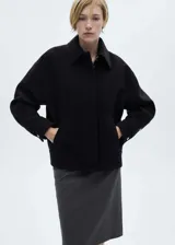 Chaqueta oversize de tejido mezcla de lana en color negro, con cuello camisero, cierre frontal de cremallera oculta, bolsillos laterales y mangas largas con puños abotonados.