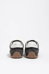 Zapatillas deportivas de perfil bajo confeccionadas en serraje color gris, con cordones claros y suela de goma con tachuelas características.