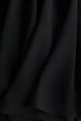 Blusa corta de tejido liviano con diseño oversized, escote redondo y mangas largas acampanadas con volados. Presenta costura fruncida en el pecho que aporta volumen y abertura en V en la espalda.