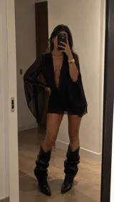 Vestido corto negro de microtul transparente, con escote pronunciado en V y mangas largas amplias tipo campana.