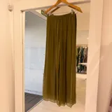 Pantalón palazzo plisado de tiro alto, confeccionado en tela liviana con caída fluida en tono verde oliva.