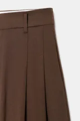 Pantalón de tiro medio color marrón, con pinzas en el delantero, perneras anchas de corte recto y trabillas para cinturón. Cuenta con bolsillos laterales y traseros, y cierre frontal con cremallera y botón.