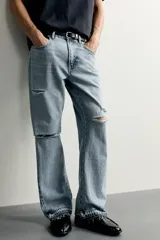 Jeans flare fit de denim negro, tiro medio, ajustados arriba y con botamanga acampanada. Cuentan con cinco bolsillos, lavado efecto gastado y bajo con acabado irregular. Cierre frontal con cremallera y botón.