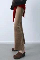 Pantalón de corte flare confeccionado en mezcla de algodón con efecto lavado. Presenta tiro medio, cintura elástica y detalles de tachas y aplicaciones bordadas en el bajo de las piernas.