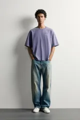 Camiseta relaxed fit de color gris con efecto lavado, cuello redondo y manga corta. Cuenta con un pequeño texto estampado en contraste en el pecho.