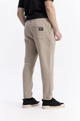 Pantalón de jogging negro de algodón y poliéster, con puños ajustados en los tobillos, cintura elástica con cordón y costuras verticales marcadas en el frente.