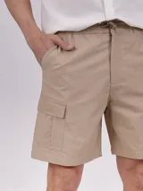 Bermuda de gabardina color verde militar, con cintura elástica ajustable con cordón, bolsillos laterales y bolsillo cargo con solapa en la pierna.