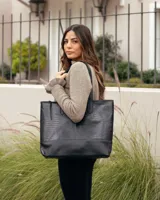 Bolso tipo tote de cuero negro con textura de reptil en la parte superior y base de cuero liso. Cuenta con doble asa de hombro.