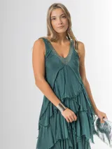 Vestido largo negro de seda italiana con diseño sin mangas de bretel ancho y escote en V profundo con detalles de paillettes plateados. Presenta múltiples capas con volados y bordes deshilachados que aportan movimiento y una caída fluida.