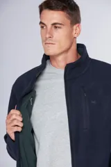 Campera de polar azul marino con cierre frontal completo, cuello alto y bolsillos laterales con cierre. Presenta un bolsillo vertical con cierre en el pecho y logo bordado.