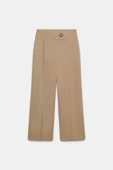 Pantalón de tiro medio con pernera ancha, confeccionado con pinzas delanteras y bolsillos laterales. Presenta un cierre frontal con cremallera y un botón decorativo dorado con relieve.