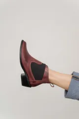 Botín negro de cuero con elásticos laterales, taco bajo y tirador trasero.