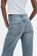 Jeans de tiro alto color negro con efecto lavado, corte mom fit, cinco bolsillos y cierre frontal con cremallera y botón metálico.